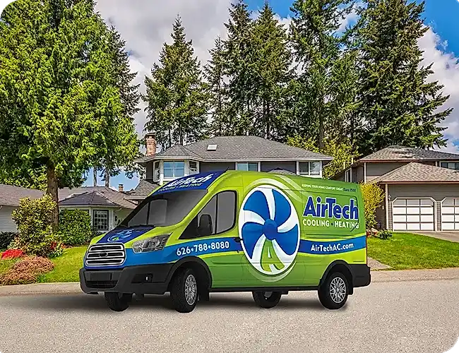 A green and blue AirTech Cooling and Heating service van parked on a suburban street in front of houses and trees.